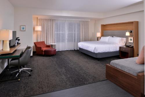 Holiday Inn & Suites - Farmington Hills - Detroit NW, an IHG Hotel في فارمنجتون هيلز: غرفة فندقية بسريرين ومكتب