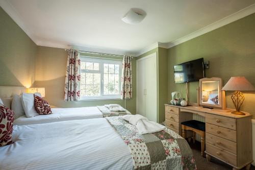 a bedroom with two beds and a desk and a television at The Hotel Balmoral - Just for Adults in Torquay