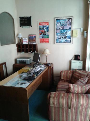 a office with a desk and a couch and a desk with a computer at Hotel Las Flores in Santiago