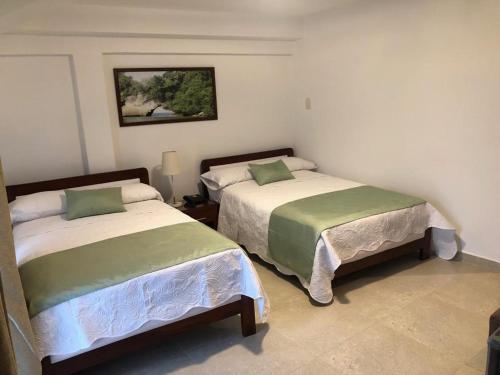 two beds sitting next to each other in a bedroom at Colon Plaza Hotel in Tumaco