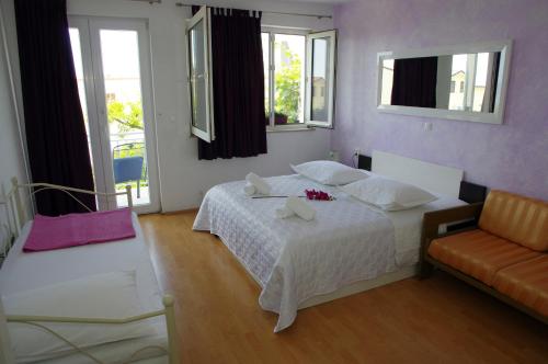 ein Schlafzimmer mit einem Bett, einem Sofa und Fenstern in der Unterkunft Apartment Lucy in Makarska
