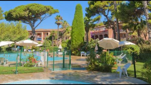 ein Pool mit Sonnenschirmen und Stühlen sowie ein Resort in der Unterkunft Entre mer et piscine in Hyères