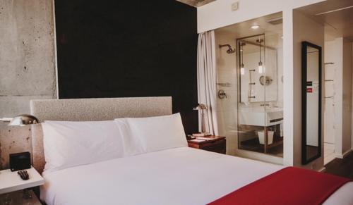 a bedroom with a large white bed and a bathroom at Nolitan Hotel SoHo - New York in New York