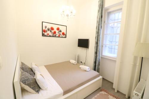 ブダペストにあるReal Apartments Wesselényi IVの白い小さなベッドルーム(ベッド1台、窓付)