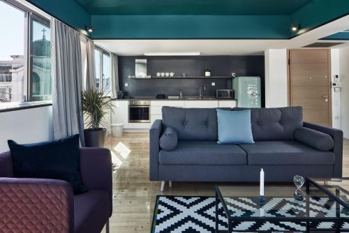 MONO Lofts في أثينا: غرفة معيشة مع أريكة زرقاء ومطبخ