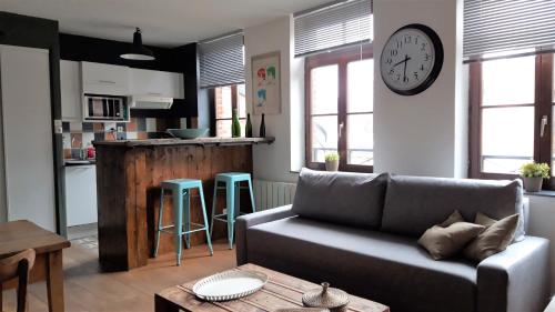 un salon avec un canapé et une horloge au mur dans l'établissement Little Suite - Louise, à Lille