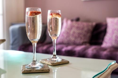 two champagne glasses on a table with a couch at Little Paris - Parking - by Brighton Holiday Lets in Brighton & Hove