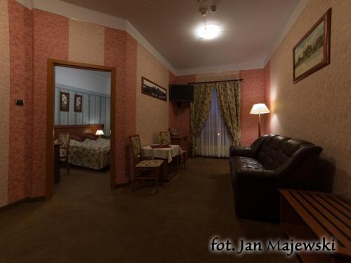 a living room with a couch and a room with a bed at Majewski Hotel & SPA in Malbork