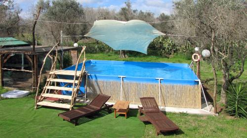 a pool with a ladder and two chairs and an umbrella at Terreno Ro-Bi-Li Ferienwohnung in Cutrofiano