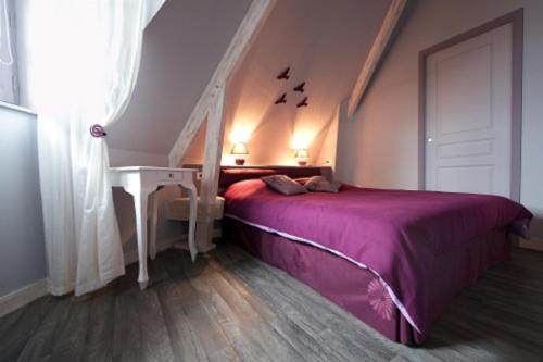 a bedroom with a bed with a purple bedspread at Gite Le Grand Manoir in Servon