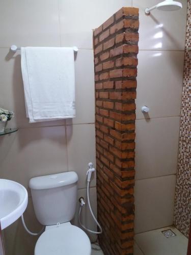 a bathroom with a brick wall next to a toilet at Pousada Recanto das Fontes in Beberibe