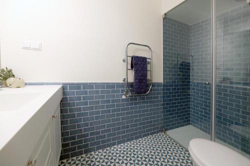 y baño con ducha de azulejos azules y aseo. en FLH Almada Cozy Apartment with View, en Oporto