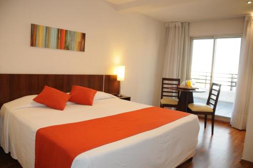una camera da letto con un grande letto con cuscini rossi di Hotel California a Montevideo