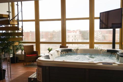 eine große Badewanne in einem Zimmer mit einem großen Fenster in der Unterkunft Kumla Hotel in Kumla