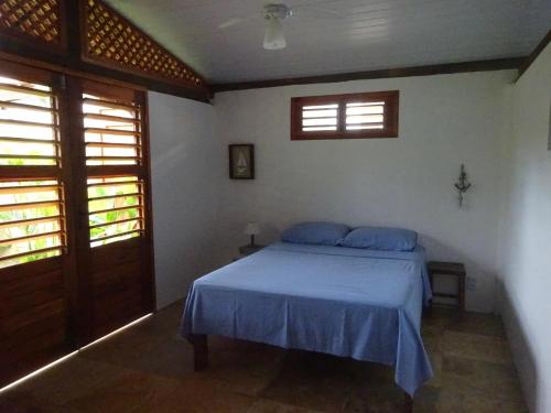 a bedroom with a bed with blue sheets and two windows at Os Navegantes B in Guajiru