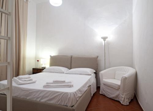 een witte slaapkamer met een bed en een stoel bij Mosca Cieca in Florence