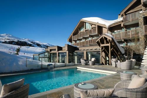 a house with a swimming pool in the snow at Hotel Annapurna in Courchevel