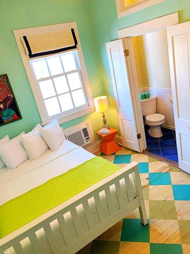 a bedroom with a bed with a window and a bathroom at Creole Gardens Guesthouse and Inn in New Orleans