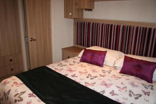 a bed with two purple pillows on top of it at Chalet 10 Dornoch Pitgrudy in Dornoch
