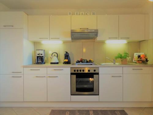 a kitchen with white cabinets and a stove top oven at Land & Meer in Hasselberg