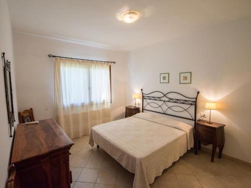 ein Schlafzimmer mit einem Bett, zwei Tischen und einem Fenster in der Unterkunft Villetta Caposchiera 400 metri dal mare in Palau