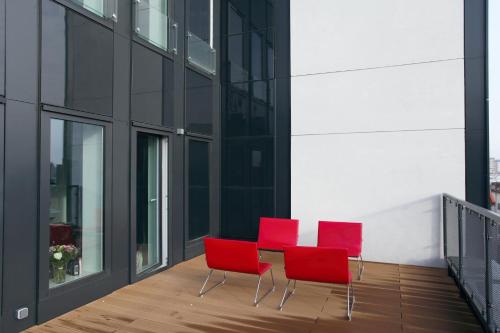 three red chairs and a table on a balcony at Space Apartments Szczecin in Szczecin