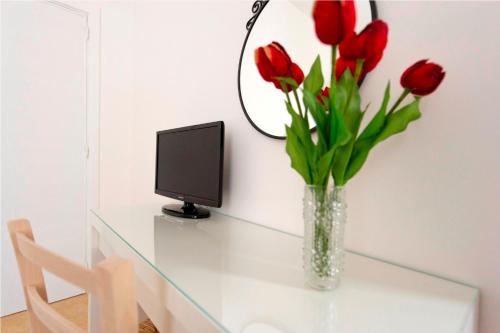 un vaso di tulipani rossi su un tavolo di vetro con un computer di Apulia Bed&Breakfast a Mattinata
