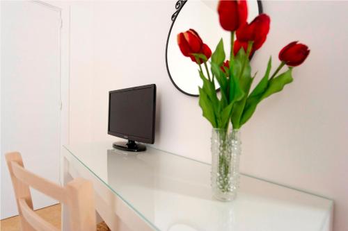 un jarrón de tulipanes rojos sobre una mesa de cristal con un ordenador en Apulia Bed&Breakfast, en Mattinata