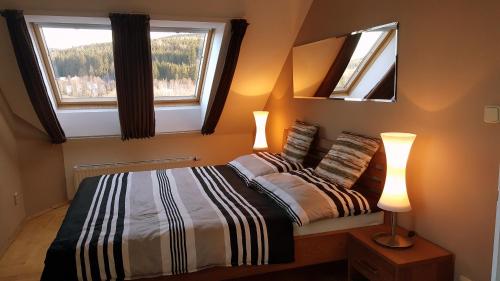 a bedroom with a bed with two windows and two lamps at Lipno Apartmany Frymburk II. in Frymburk