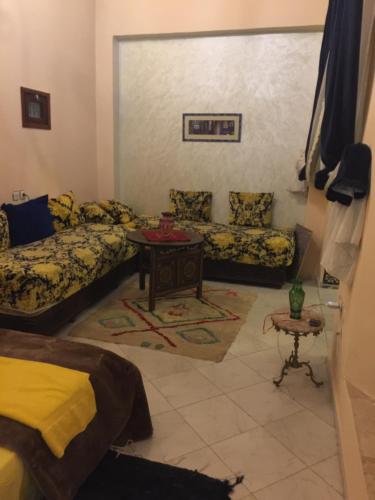 a living room with two beds and a table at Riad AlKATIB Meknès in Meknès