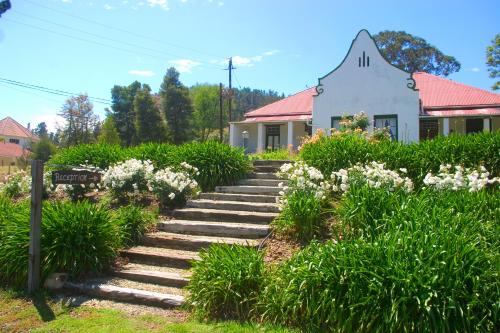 a garden with stairs leading to a white house at Over The Mountain Guest Farm in George