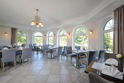 Hotel Hammermühle في Wahlrod: غرفة طعام مع طاولات وكراسي ونوافذ