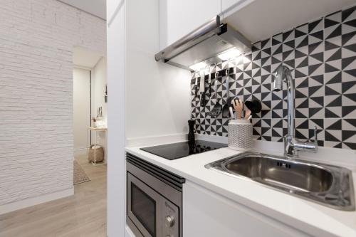cocina con fregadero y azulejos blancos y negros en Cozy Apartment Salamanca Neighborhood en Madrid