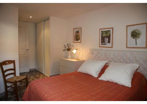 um quarto com uma cama com almofadas brancas e uma cadeira em Villa sainte claire em Amélie-les-Bains-Palalda