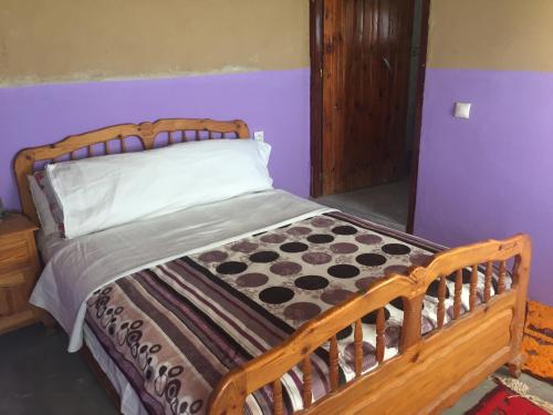 Cette chambre comprend un lit avec un cadre en bois. dans l'établissement Gîte d'étape traditionnel berbère, à Ifri