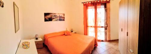 a bedroom with an orange bed and a window at Paradise House in Alcamo Marina