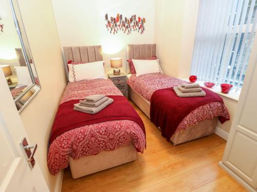Duas camas num pequeno quarto com um espelho em The River Appartment em Todmorden