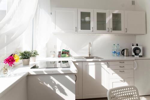una cocina blanca con armarios blancos y fregadero en Warsaw Budget Apartments, en Varsovia