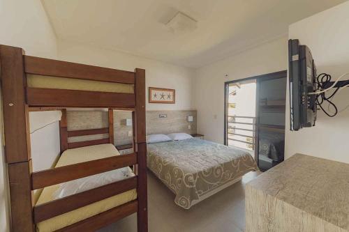 a bedroom with a bunk bed and a television at Parador Tropical in Bombinhas
