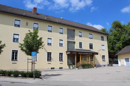 ein großes gelbes Gebäude mit einem Parkschild davor in der Unterkunft Hotel und Gasthof Soller in Ismaning