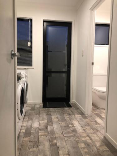 a laundry room with a black door and a washing machine at Trendy Bungalow in the Heart of Rotorua in Rotorua
