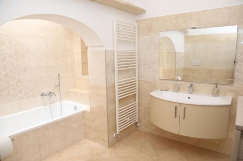 bagno con lavandino, vasca e specchio di L'ANTICA PIETRA Casa Vacanza Salento a Poggiardo