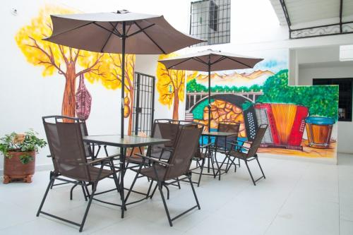 uma mesa e cadeiras com guarda-sóis em frente a uma pintura em Aparta Hotel El Cacique Upar em Valledupar