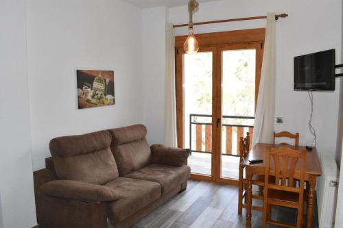 a living room with a brown couch and a sliding glass door at MONTE PIEDRA in Arroyo Frio