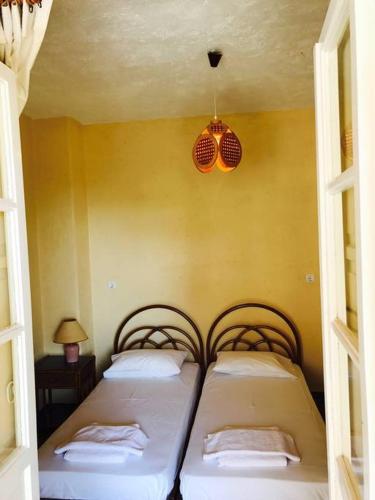 two twin beds in a room with yellow walls at PALIO LIMANI APARTMENTS in Spetses