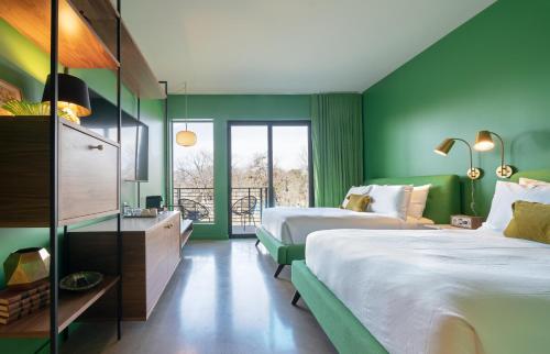 una camera d'albergo con due letti e pareti verdi di The Ruby Hotel a Round Rock
