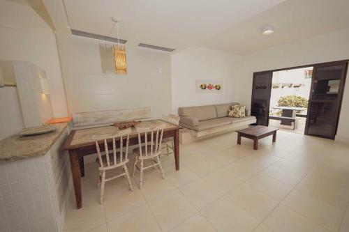 a kitchen and living room with a table and chairs at Parador Tropical in Bombinhas