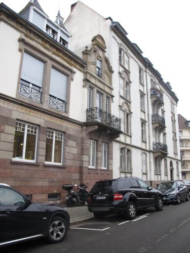un grand bâtiment avec des voitures garées devant dans l'établissement CityCosy Strasbourg - T2 Hirtz Orangerie, à Strasbourg