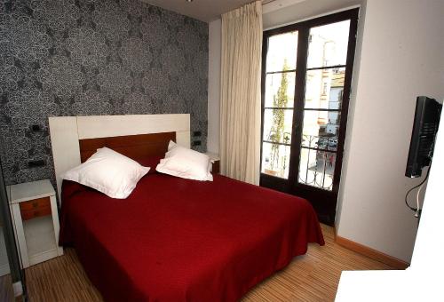 a bedroom with a red bed and a window at Hostal Centro in Soria