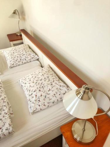 a bed with two pillows and a lamp on a table at Kap Café in Kaplice